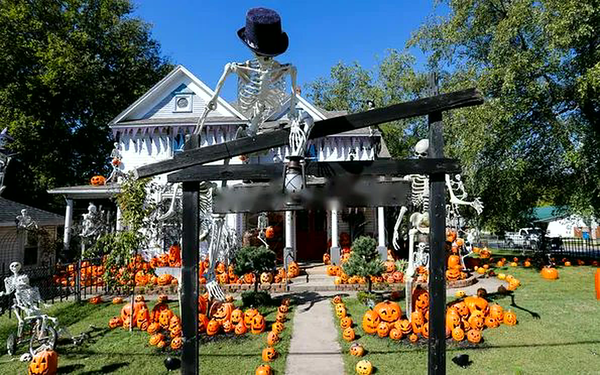 Front yard lined with hundreds of pumpkins and a skeleton entry arch
